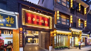 A traditional Chinese building with a signboard, wooden doors, and lanterns. - Fenghuang Story Hotel (Xiangxi)