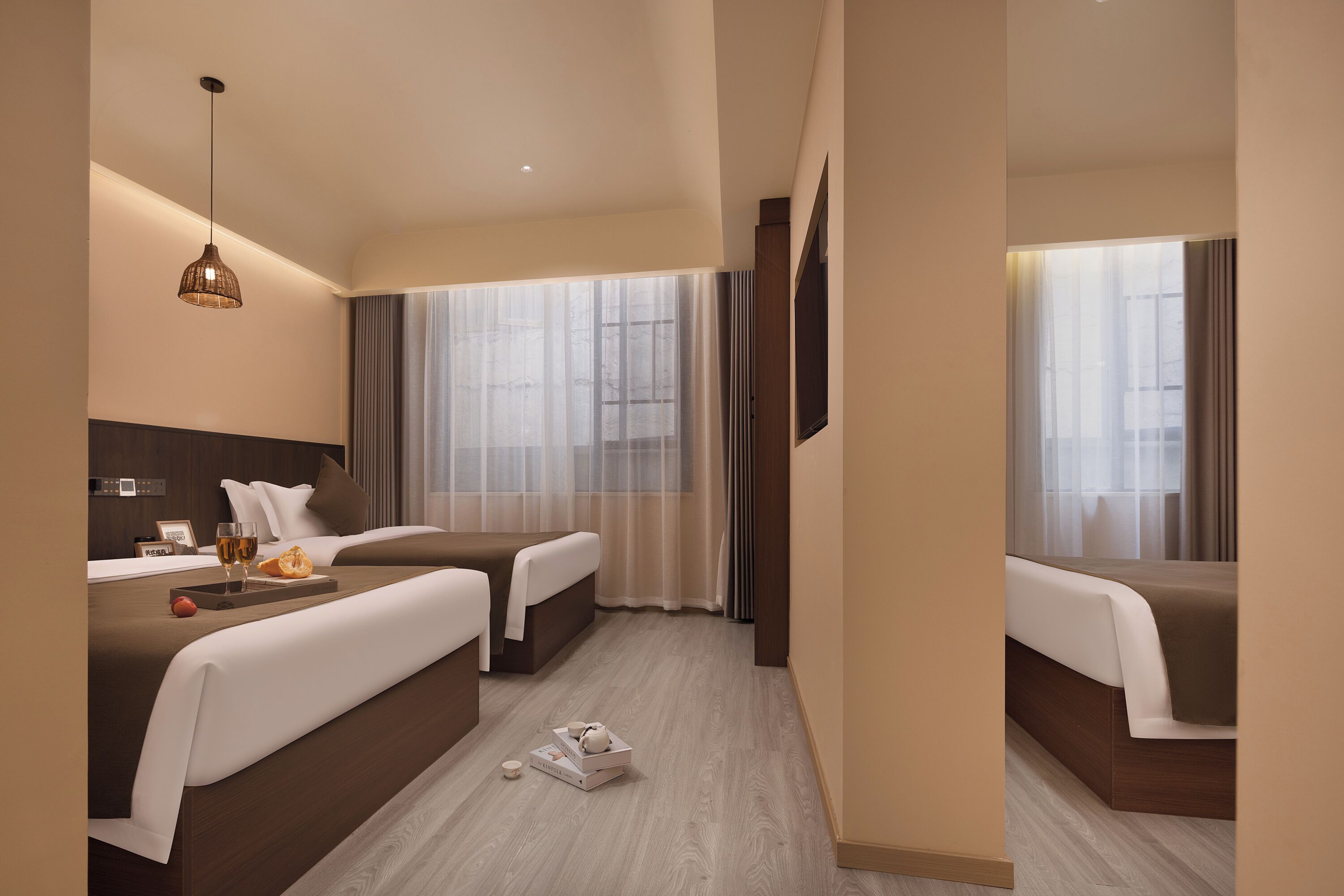 A hotel room with two beds, a large window with curtains, a flat-screen TV, and a small table with a tray.