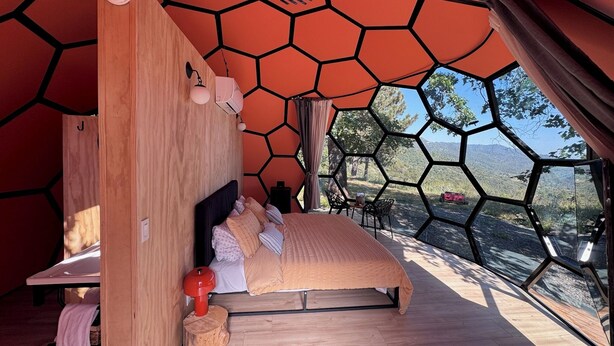A bedroom with a bed, wooden headboard, and a view of the outdoors.