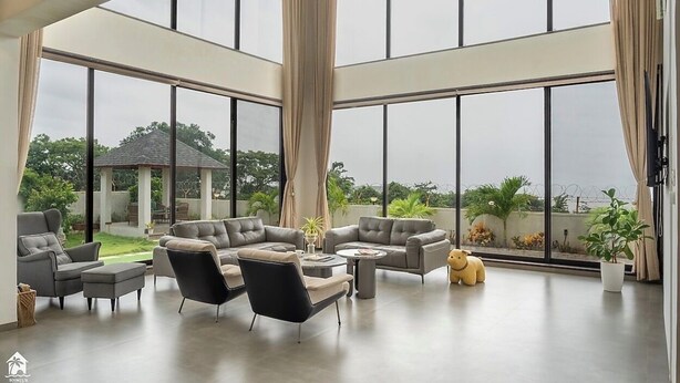 A spacious living area with large windows, modern furniture, and a view of the outdoors. - on the hill by the sea (Chandikanagar, Maharashtra)
