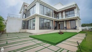 A modern two-story house with large windows, a flat roof, and a well-maintained lawn. - on the hill by the sea (Chandikanagar, Maharashtra)