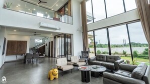 A spacious living area with a dining set, sofas, and a large window offering a view of the outdoors. - on the hill by the sea (Chandikanagar, Maharashtra)