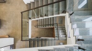 A modern staircase with glass railings and a concrete wall. - on the hill by the sea (Chandikanagar, Maharashtra)