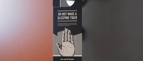 A door with a black and white sign that reads 'DO NOT WAKE A SLEEPING TIGER' and a hand illustration.