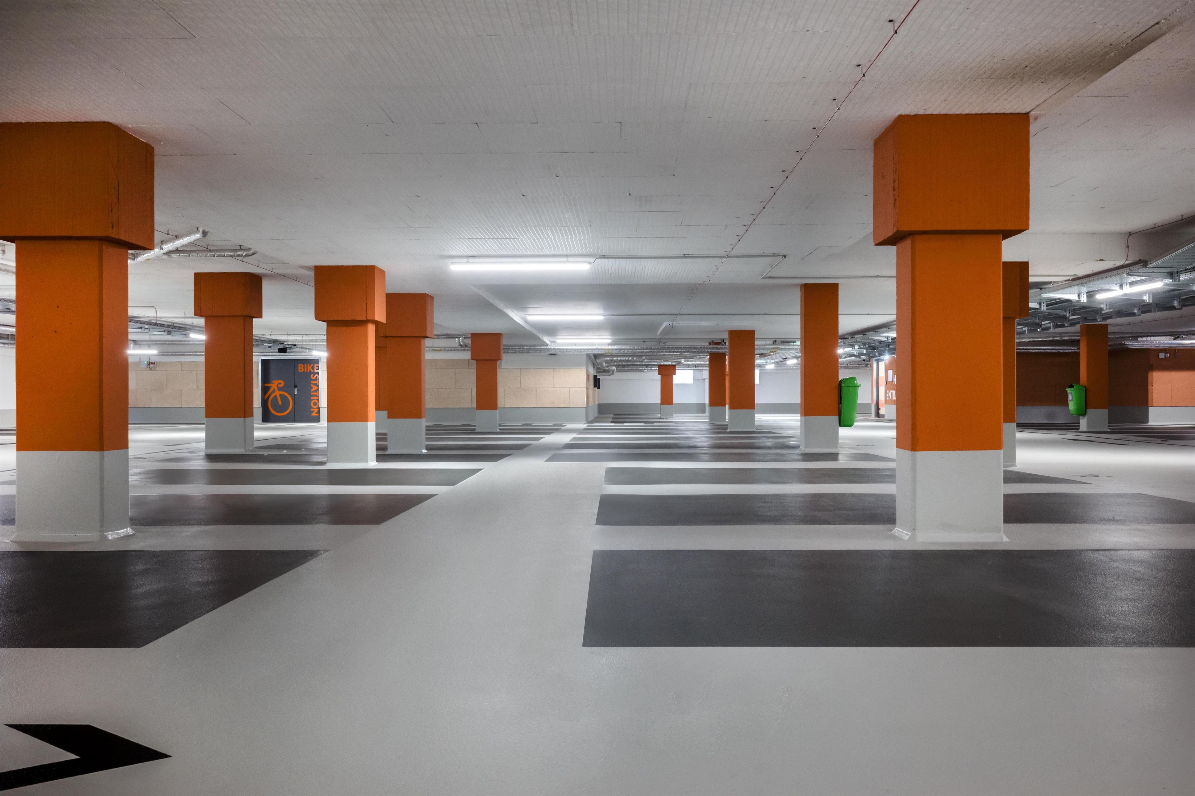 Ett parkeringsgarage med orange pelare och vita golv, med en särskild plats för cykelparkering.