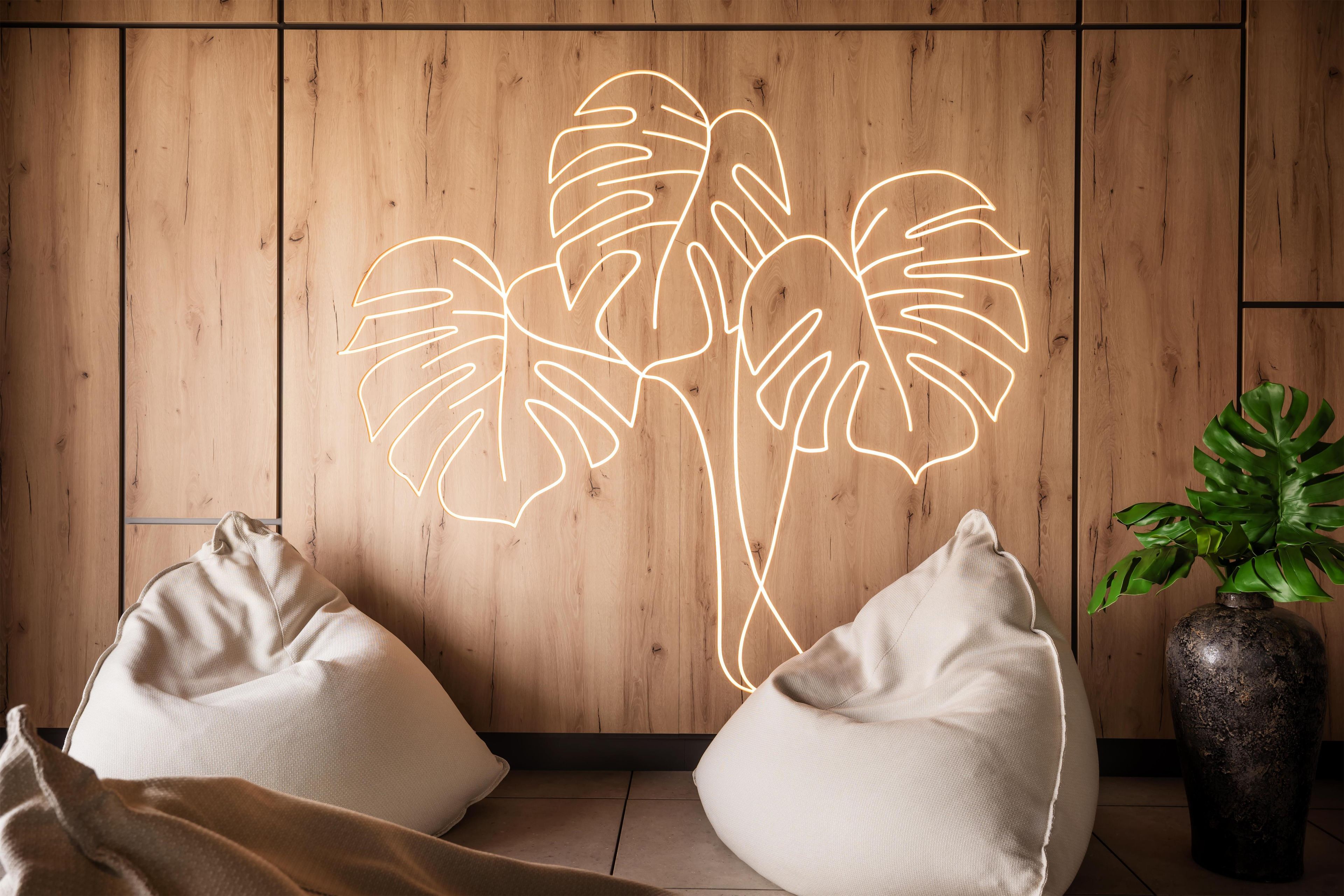 Una habitación con paneles de madera, dos pufs y una planta en maceta.