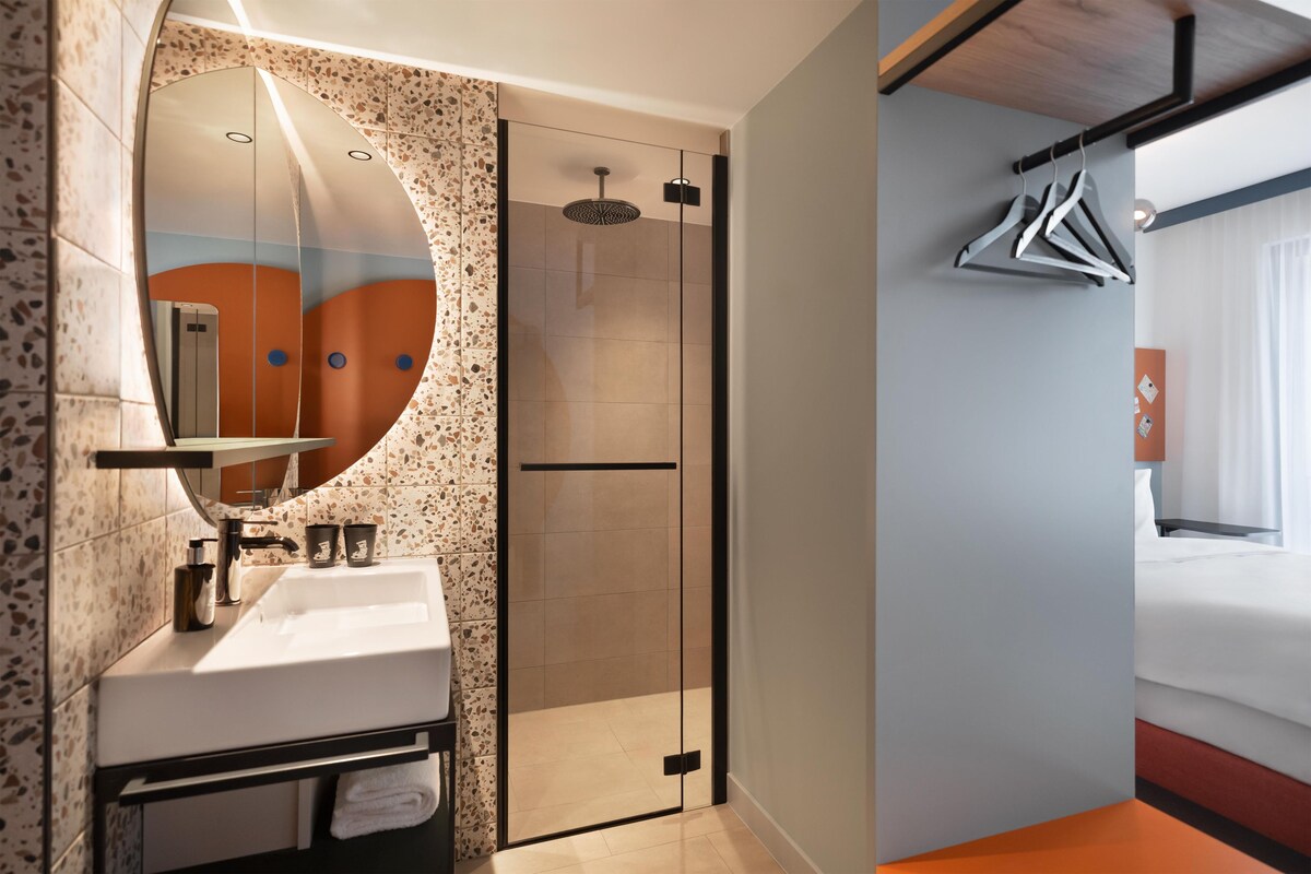 Un bany modern amb dutxa trencadissa, un lavabo amb mirall i un suport per a tovalloles.