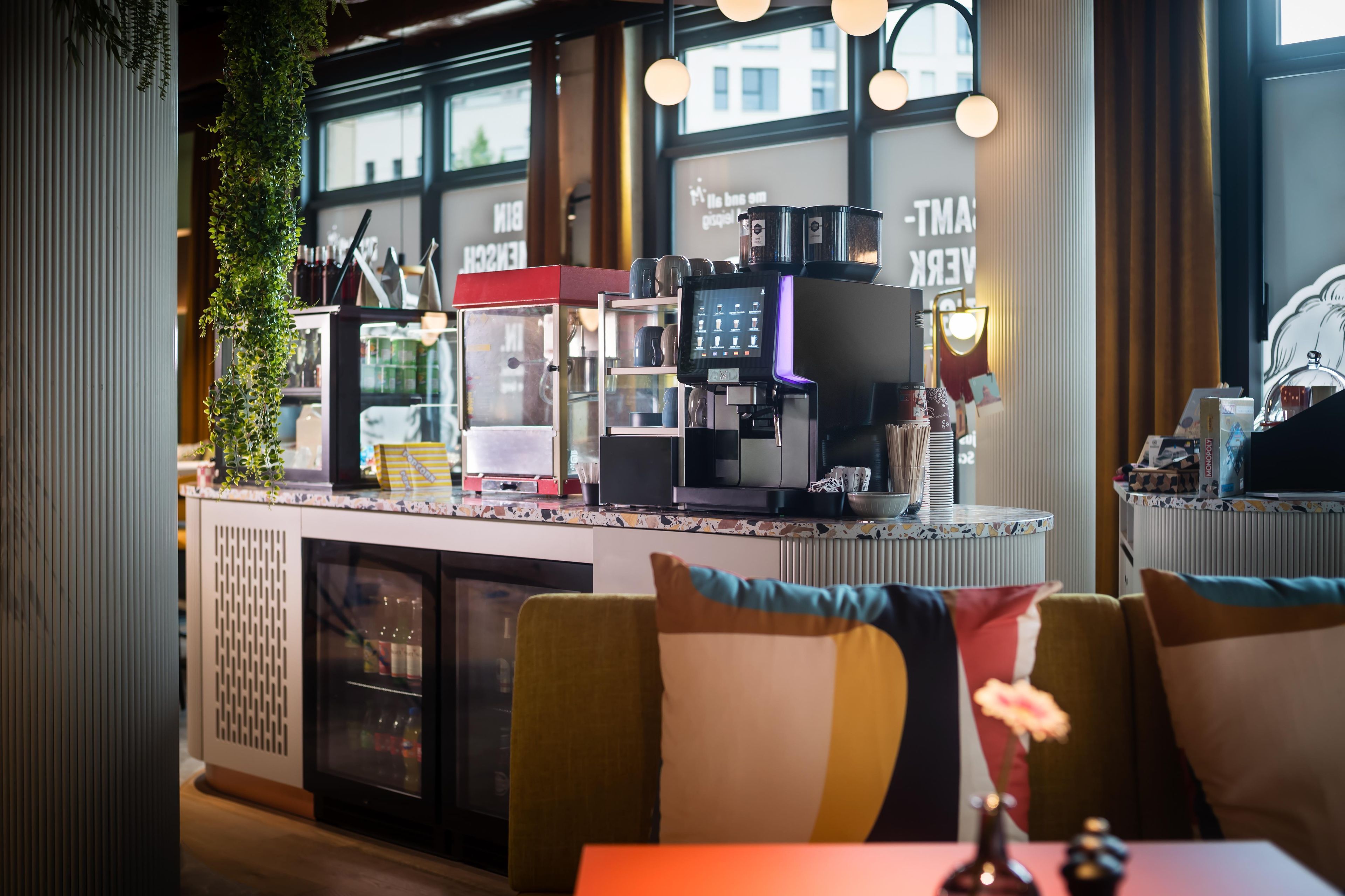Zona de bar con máquina de café, asientos y vistas a la calle.
