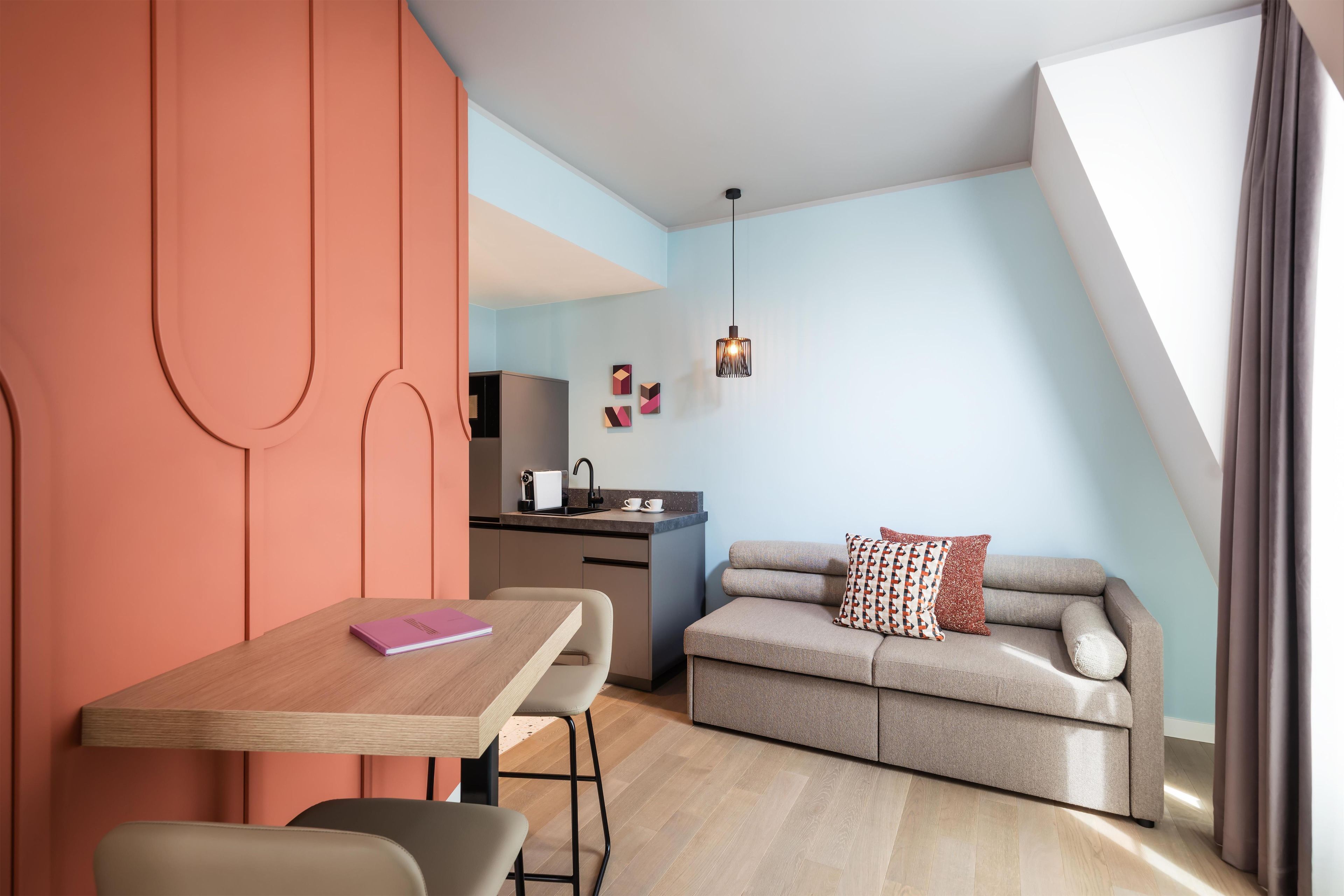 Un apartamento moderno con comedor, kitchenette y un sofá con cojín estampado.