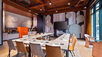 Una sala de conferencias moderna con una larga mesa, sillas y una pantalla de televisión.