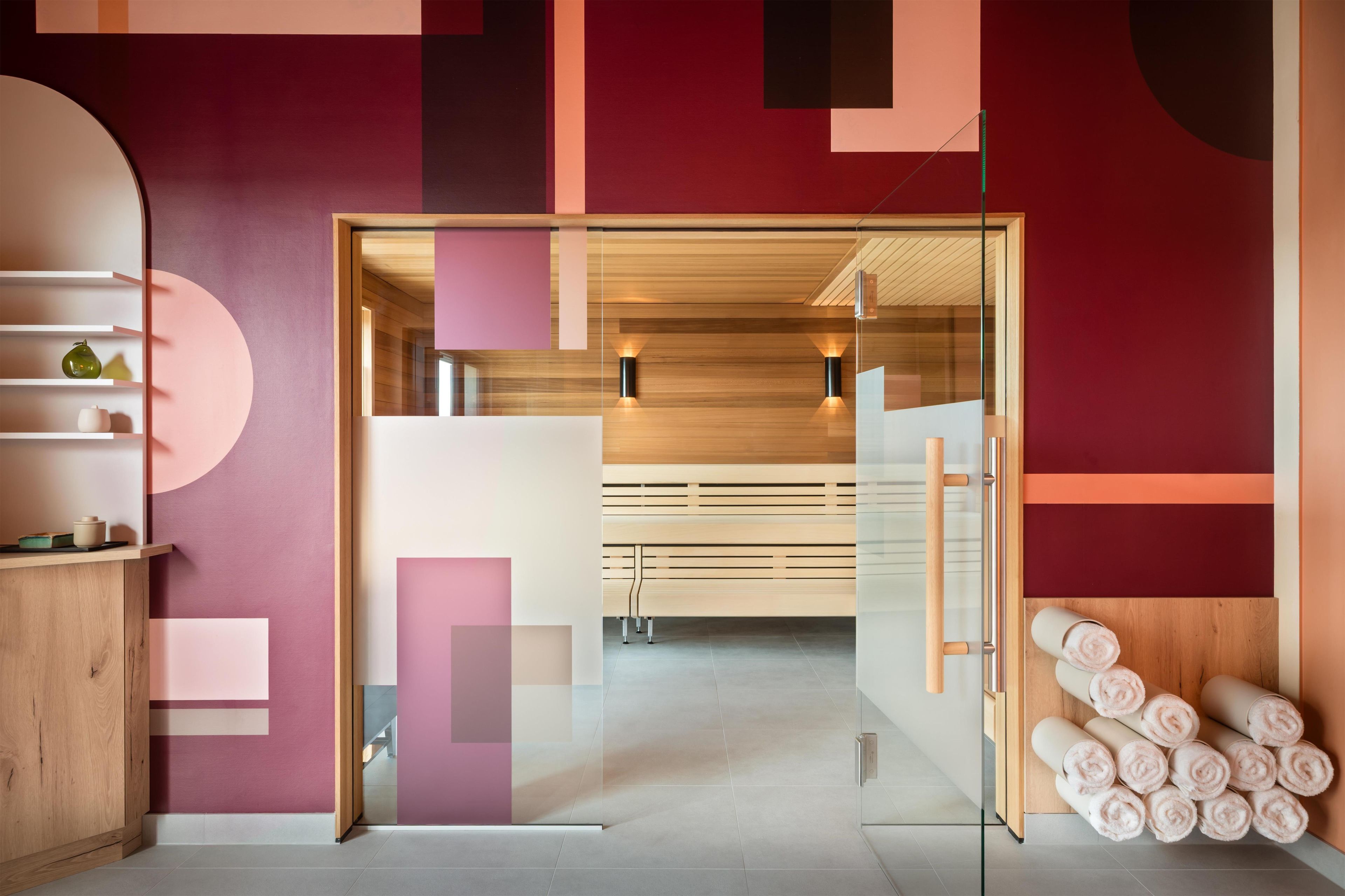 A modern interior with a glass partition, wooden furniture, and a visible seating area.