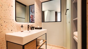 Un baño moderno con lavamanos blanco, espejo y toallero.