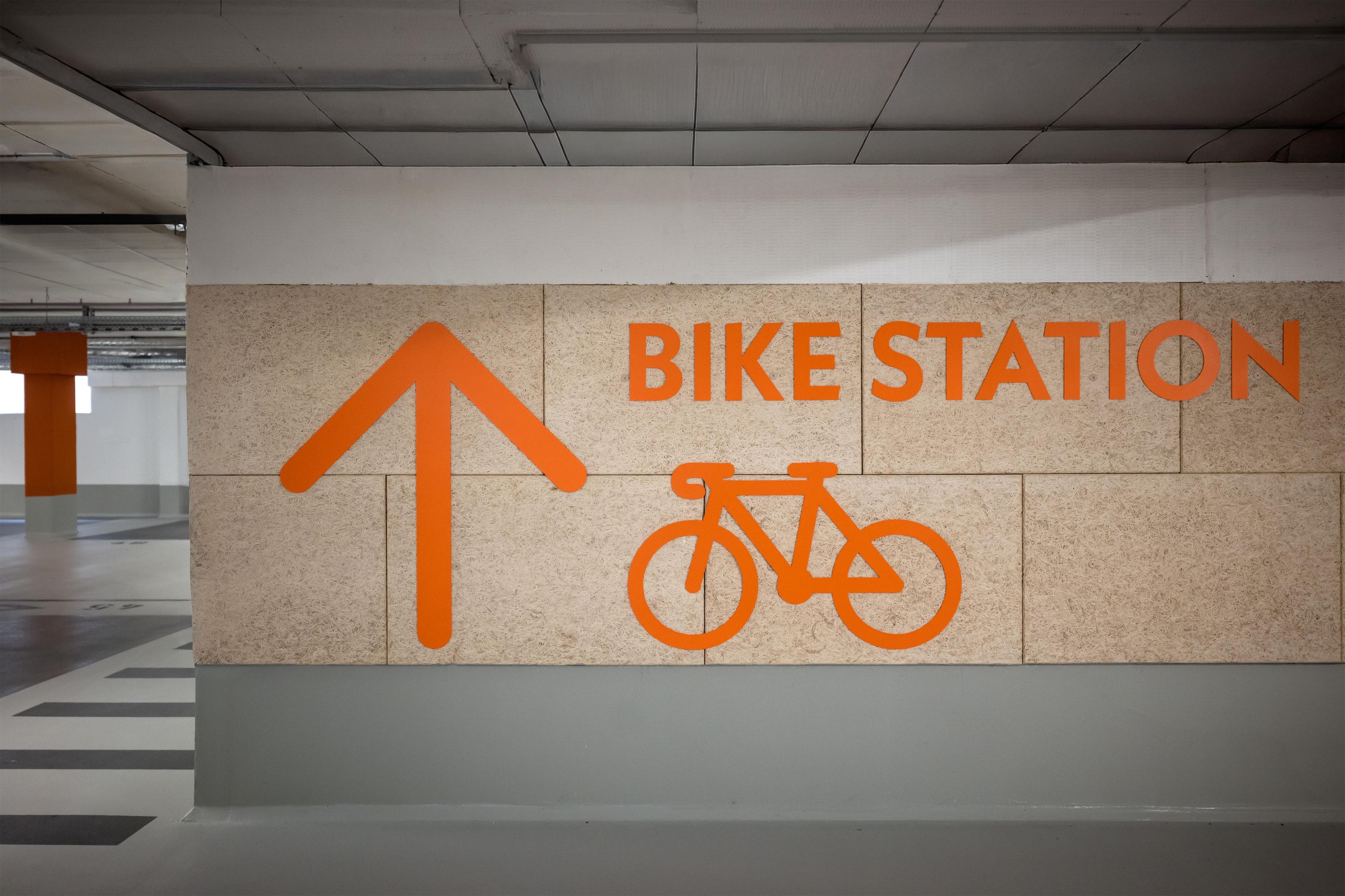 A wall with a directional arrow and a bicycle symbol indicating a bike station.