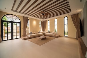 A spacious living room with a large sofa, a coffee table, and a ceiling fan.