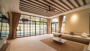 Amplia sala de estar con un gran ventanal, ventilador de techo, sofá y una mesa de centro.