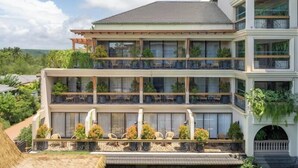 A multi-story hotel with balconies, outdoor seating, and lush greenery. - The Evren, Vagator (GOA)