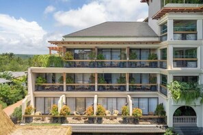A multi-story hotel with balconies, outdoor seating, and lush greenery. - The Evren, Vagator (GOA)