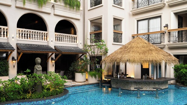A hotel with a swimming pool, a thatched-roof bar, and multiple balconies. - The Evren, Vagator (GOA)