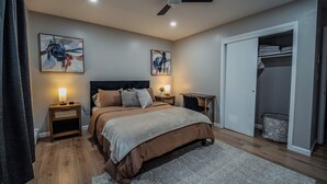Quarto com cama, mesas de cabeceira, ventilador de teto e guarda-roupa.
