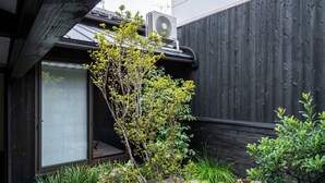 Een traditionele Japanse tuin met een pad van stenen, rotsen begroeid met mos en een kleine boom.