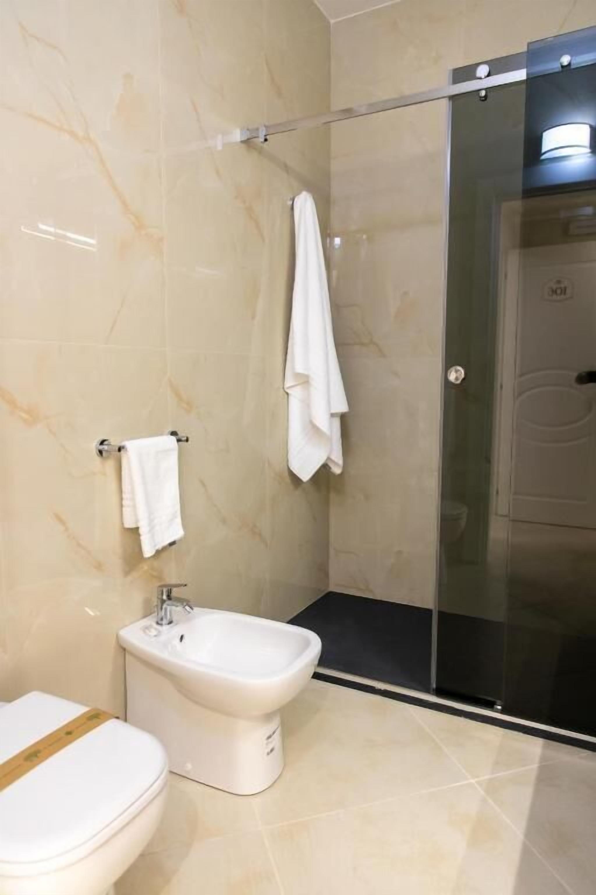 Un baño moderno con inodoro, bidé y cabina de ducha de vidrio.