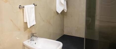 Un baño moderno con inodoro, bidé y cabina de ducha de vidrio.