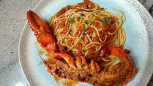 A plate of spaghetti with a lobster tail and a tomato-based sauce. - GLOBAL HOTEL (San Ferdinando)