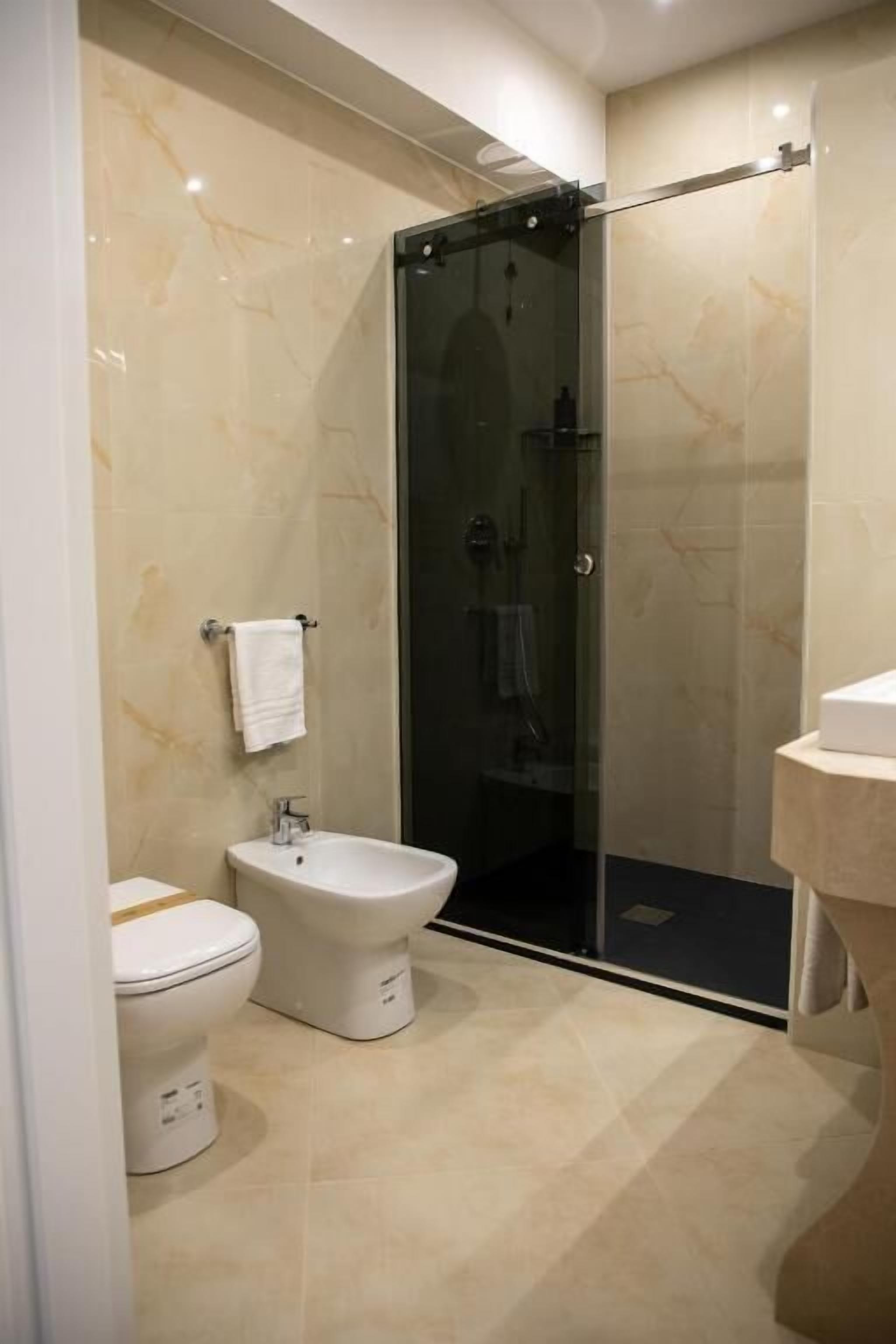 A modern bathroom with a toilet, bidet, and glass-enclosed shower.