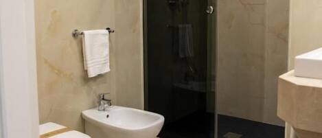 A modern bathroom with a toilet, bidet, and glass-enclosed shower.