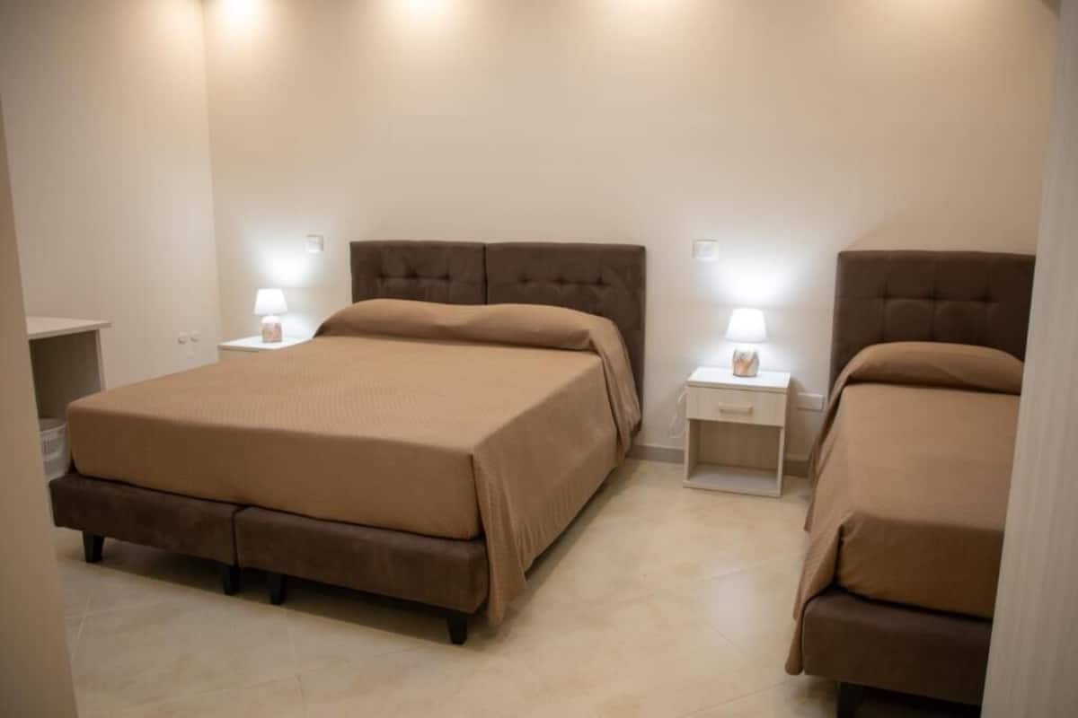 A bedroom with a large bed, two bedside tables with lamps, and a small nightstand.