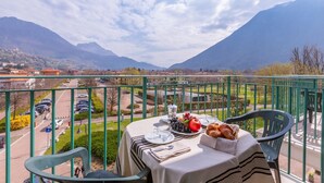 Un balcón con una mesa dispuesta para el desayuno, con vistas a un paisaje montañoso.