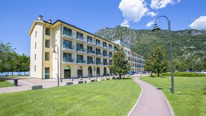 Un hotel de varios pisos con fachada amarilla, un patio central y montañas al fondo.