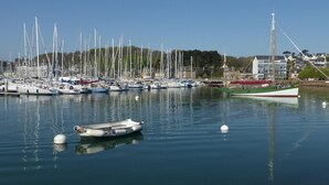 Un port de plaisance où sont amarrés divers bateaux, un voilier remarquable portant le numéro d’immatriculation PL 643920, et un bâtiment avec une haute structure en arrière-plan.