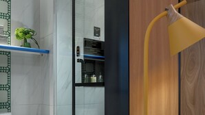 A modern bathroom with a glass shower enclosure, a white toilet, a trash bin, and a wicker basket. - Lijiang MAISON Hotel (Lijiang)