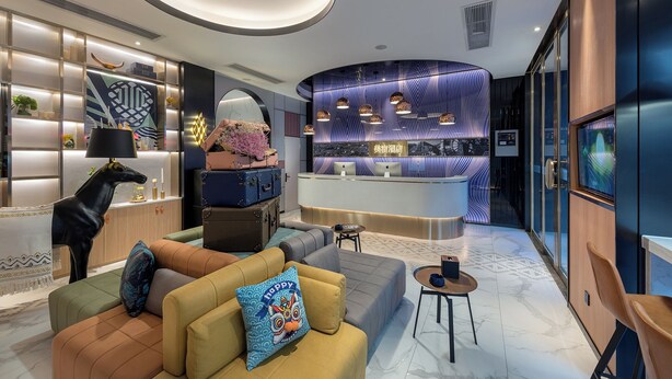 A modern hotel lobby with a reception desk, seating area, and decorative elements like a horse statue and patterned wall. - Lijiang MAISON Hotel (Lijiang)