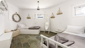 A bedroom with a bed, a small table, a chair, a wardrobe, a mirror, and a window. - Paros 3 bedrooms Maisonette for 6 persons by MPS (Molos)