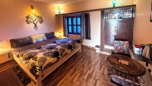 Tunnelmallinen makuuhuone, jossa on puinen sänky, yöpöytä lampulla, ikkuna verhoilla ja ovi koristeellisella paneelilla.