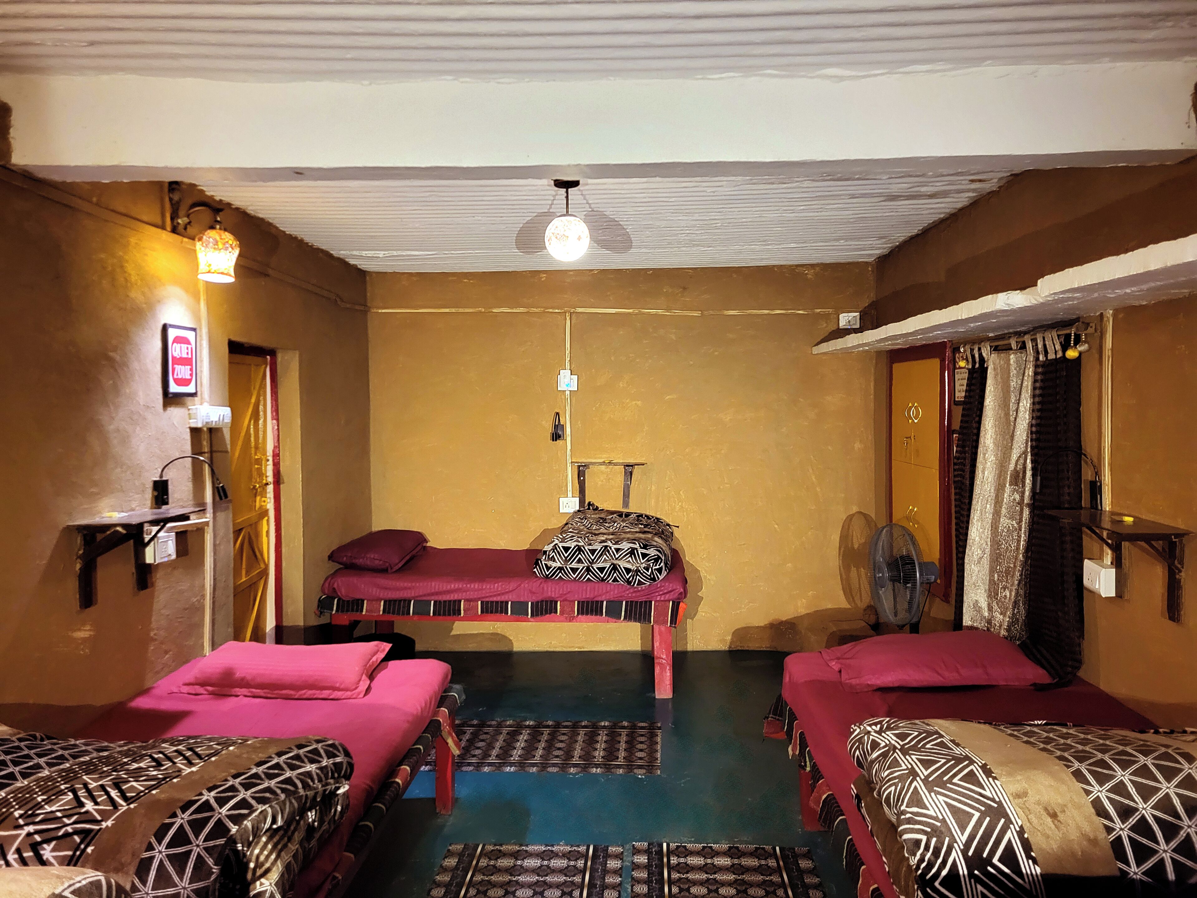 Ein Zimmer mit zwei Betten, einem Deckenventilator, einer Wandleuchte und einer Tür mit einem 'Betreten Verboten'-Schild.