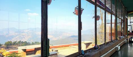 Una habitación con ventanas amplias que ofrecen vistas a un paisaje montañoso.