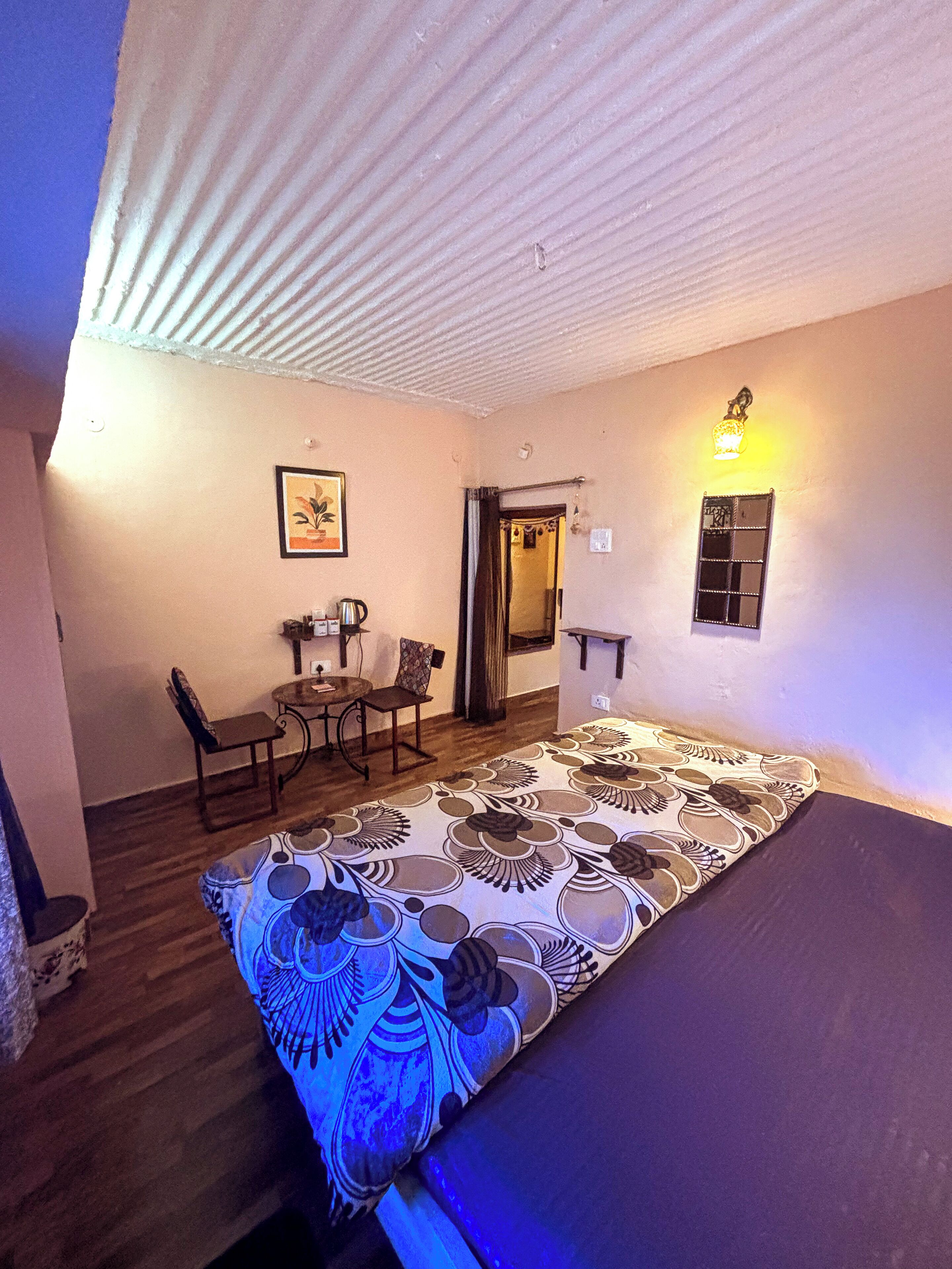 A room with a bed, a dining table with chairs, a small kitchen area, and a bathroom door.