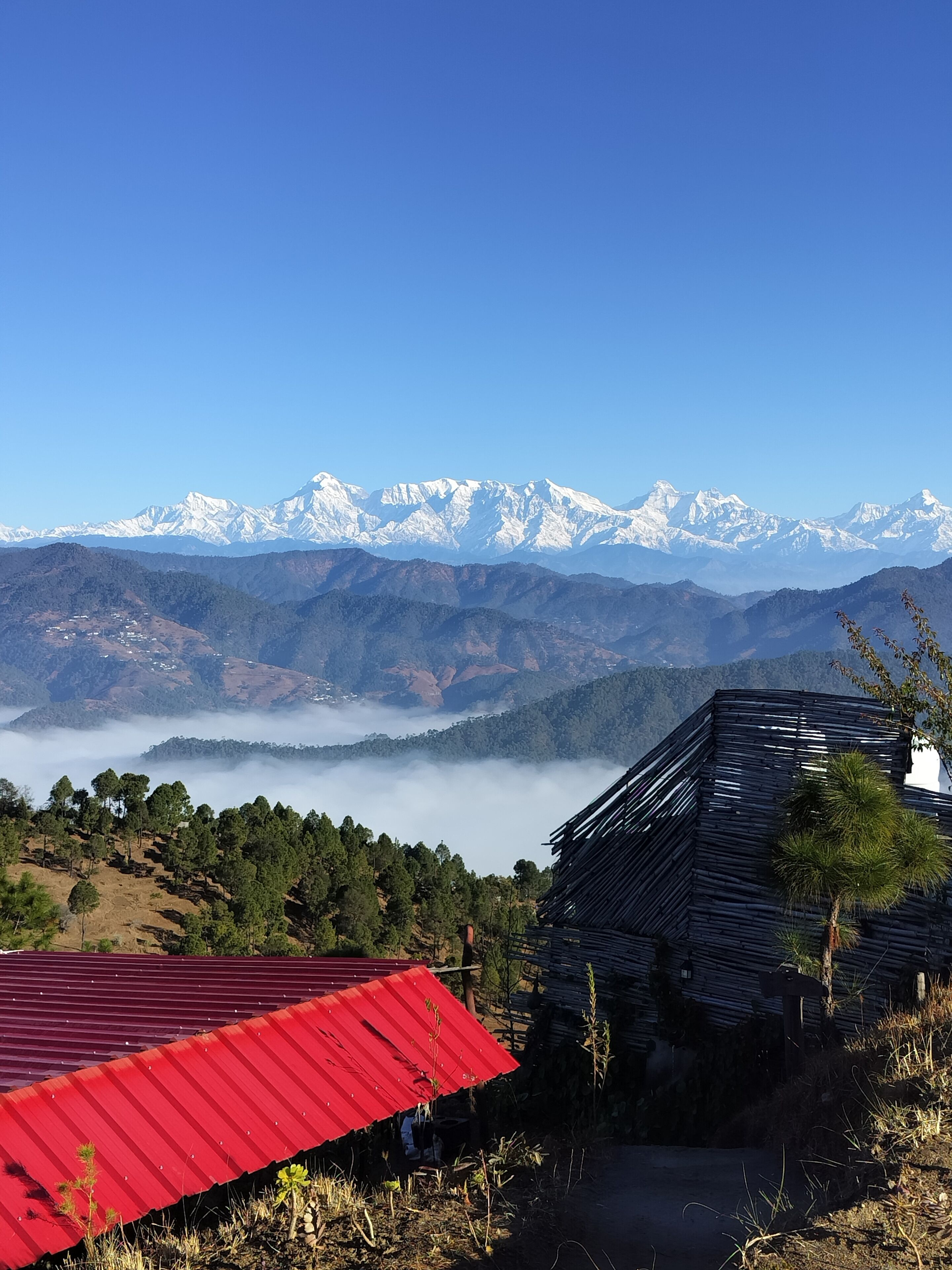 A mountainous landscape with snow-capped peaks in the background, a red-roofed building in the foreground, and a path leading towards the mountains.