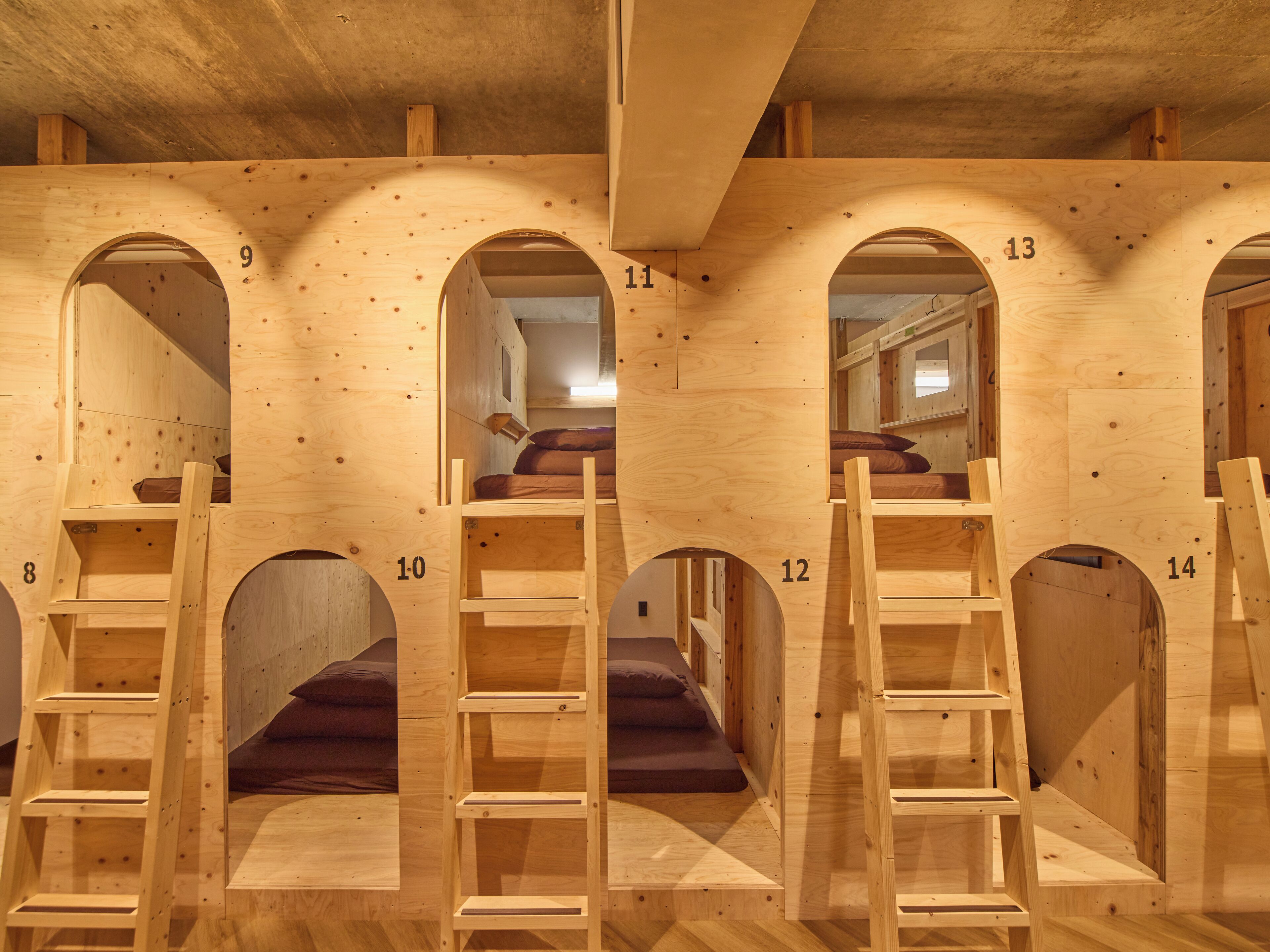 A series of wooden bunk beds with numbered compartments, each with a ladder and a mattress.