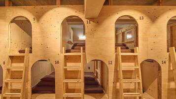 A series of wooden bunk beds with numbered compartments, each with a ladder and a mattress.