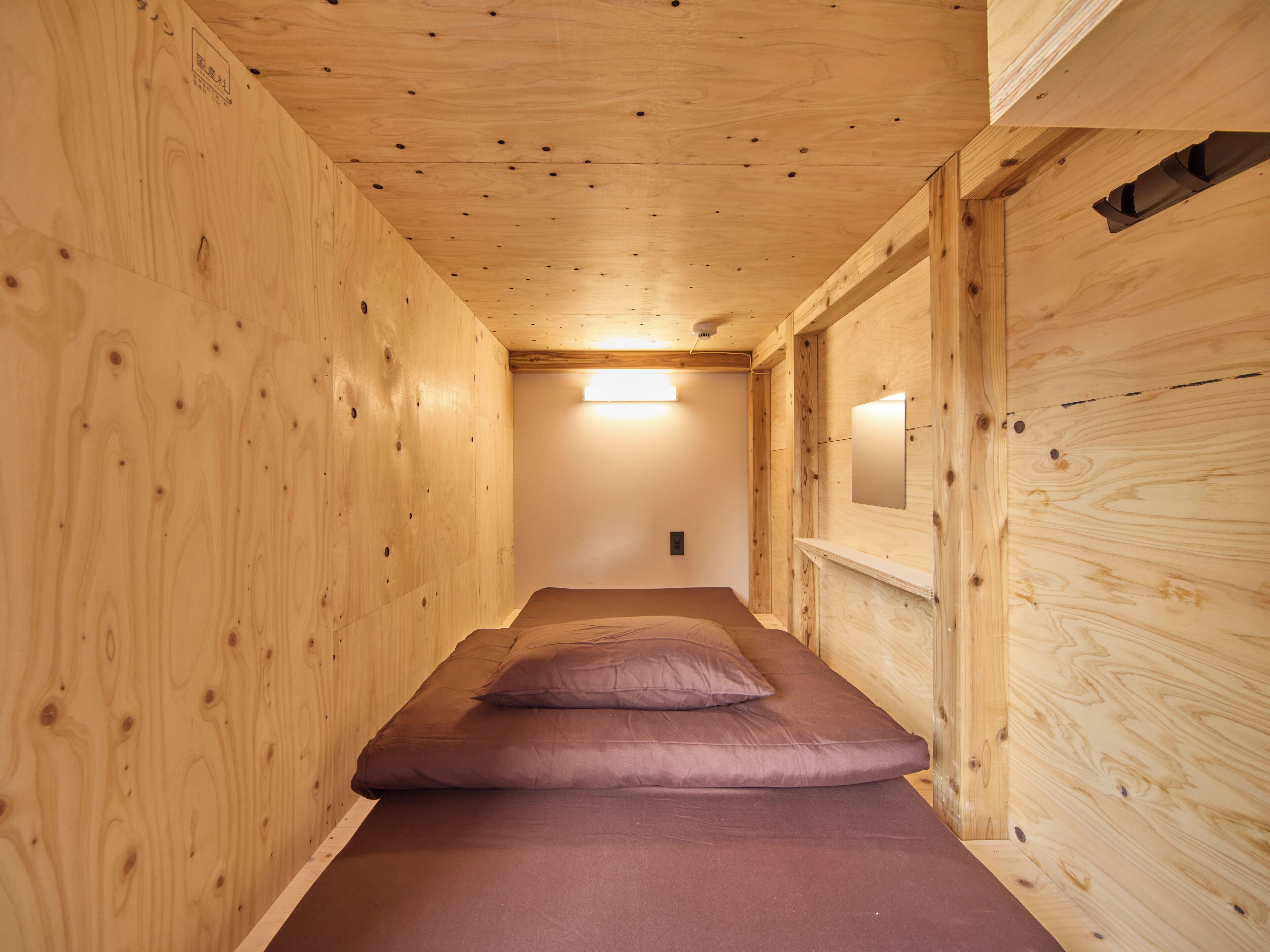 A narrow wooden room with a bed and a small window.