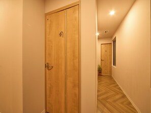 A hallway with wooden doors, a potted plant, and a wooden floor. - Southern Gate HIVE (Ishigaki)