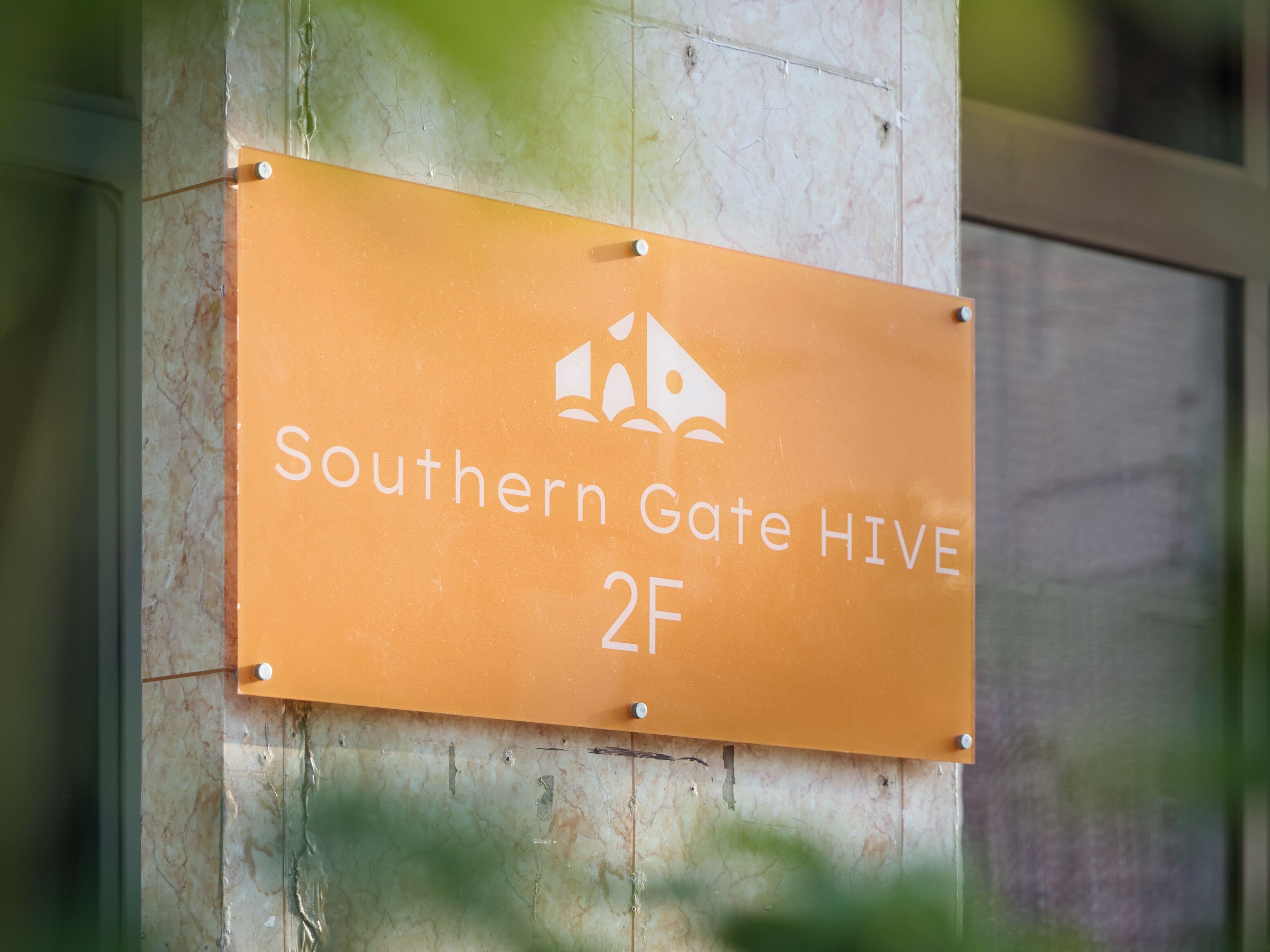 Une enseigne indiquant « Southern Gate Hive 2F » est fixée sur la façade d’un immeuble.