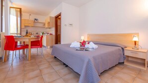 Quarto de hotel com cama, mesa de cabeceira e uma pequena escrivaninha com cadeira.