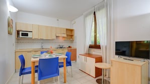 Uma cozinha compacta com micro-ondas, fogão e área de jantar com cadeiras azuis.