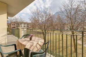 A balcony with a table and chairs, a potted plant, and a view of a mountain and trees. - Studio in Porlezza am Luganersee (Porlezza)