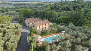 Uma villa com piscina, rodeada por oliveiras e vista para o campo.